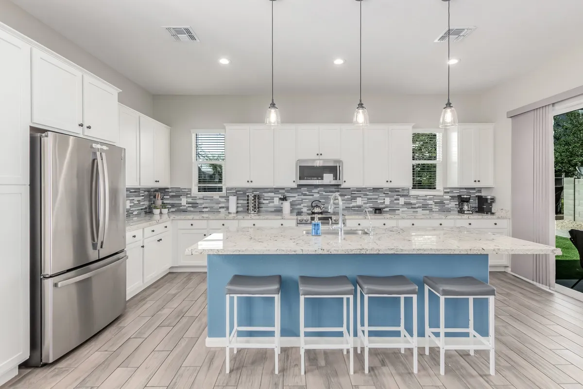 This image showcases a contemporary kitchen highlighted by granite countertops, a spacious kitchen island, and gleaming stainless steel appliances. Stylish pendant lighting hangs over the island, illuminating an inviting workspace ideal for both meal preparation and casual gatherings.