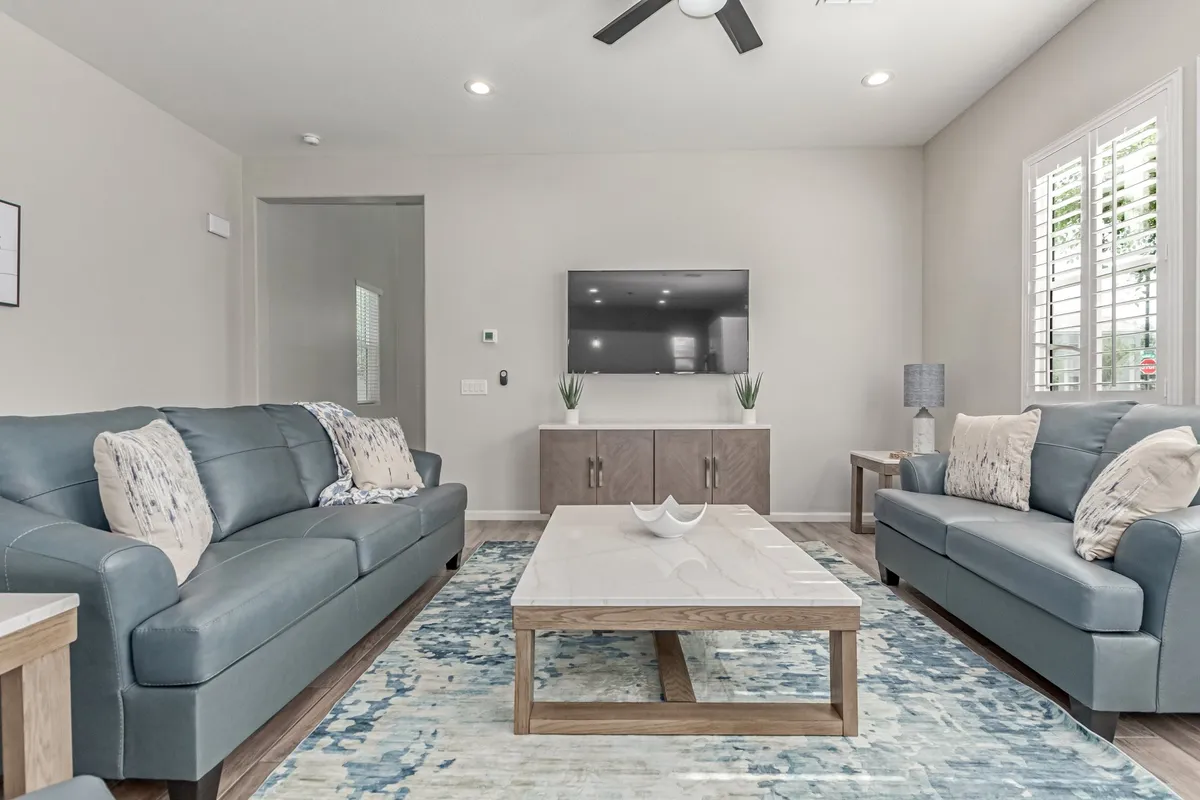 A welcoming living room with a comfortable sofa, coffee table, television, and a cozy rug, designed for both relaxation and socializing. The space is inviting, suggesting easy conversation or watching the game highlights.
