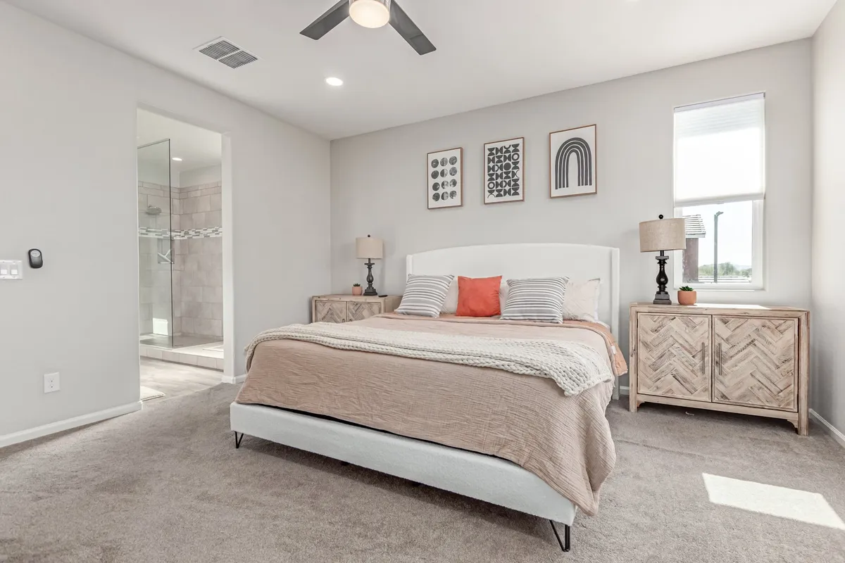 A cozy bedroom scene with a neatly made bed, tasteful artwork on the walls, and nightstands with elegant lamps. The soft lighting and harmonious decor create a welcoming, peaceful environment ideal for relaxation or reading before bed.